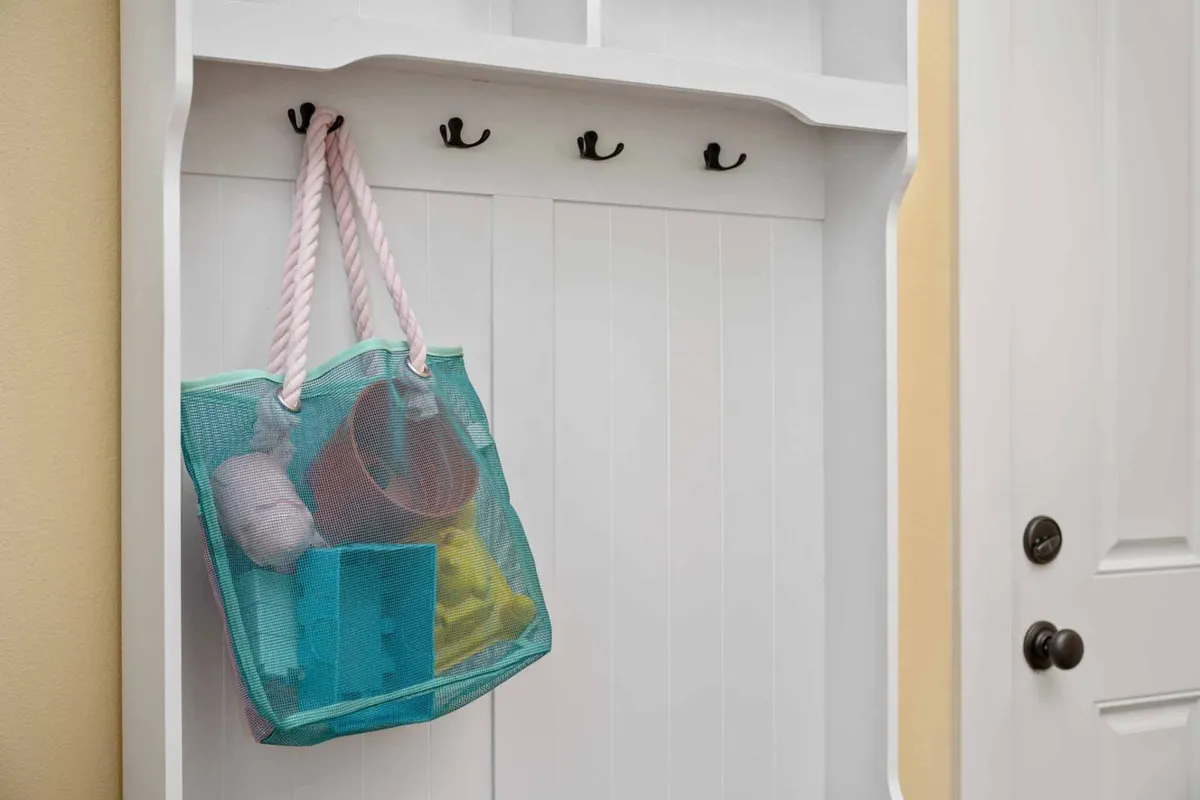 A playful mesh bag filled with colorful toys hangs on wall hooks, hinting at a family-friendly atmosphere and readiness for children’s activities. The setting is bright and inviting, evoking the anticipation of playtime and shared family fun.