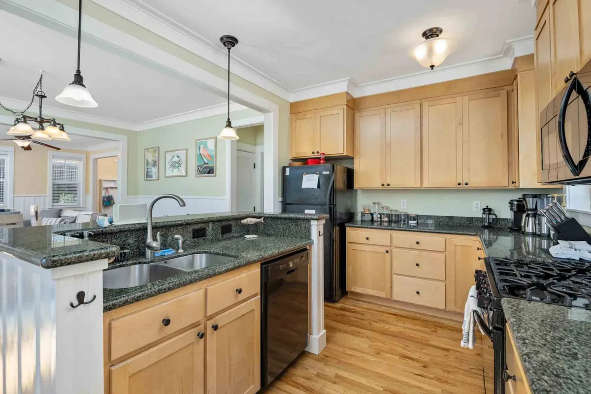 This image showcases a modern kitchen with granite countertops, stainless steel appliances, pendant lighting, and a central island. The warm and welcoming atmosphere is highlighted by the open layout, making it an ideal gathering spot for family and friends during meal preparation and cooking.