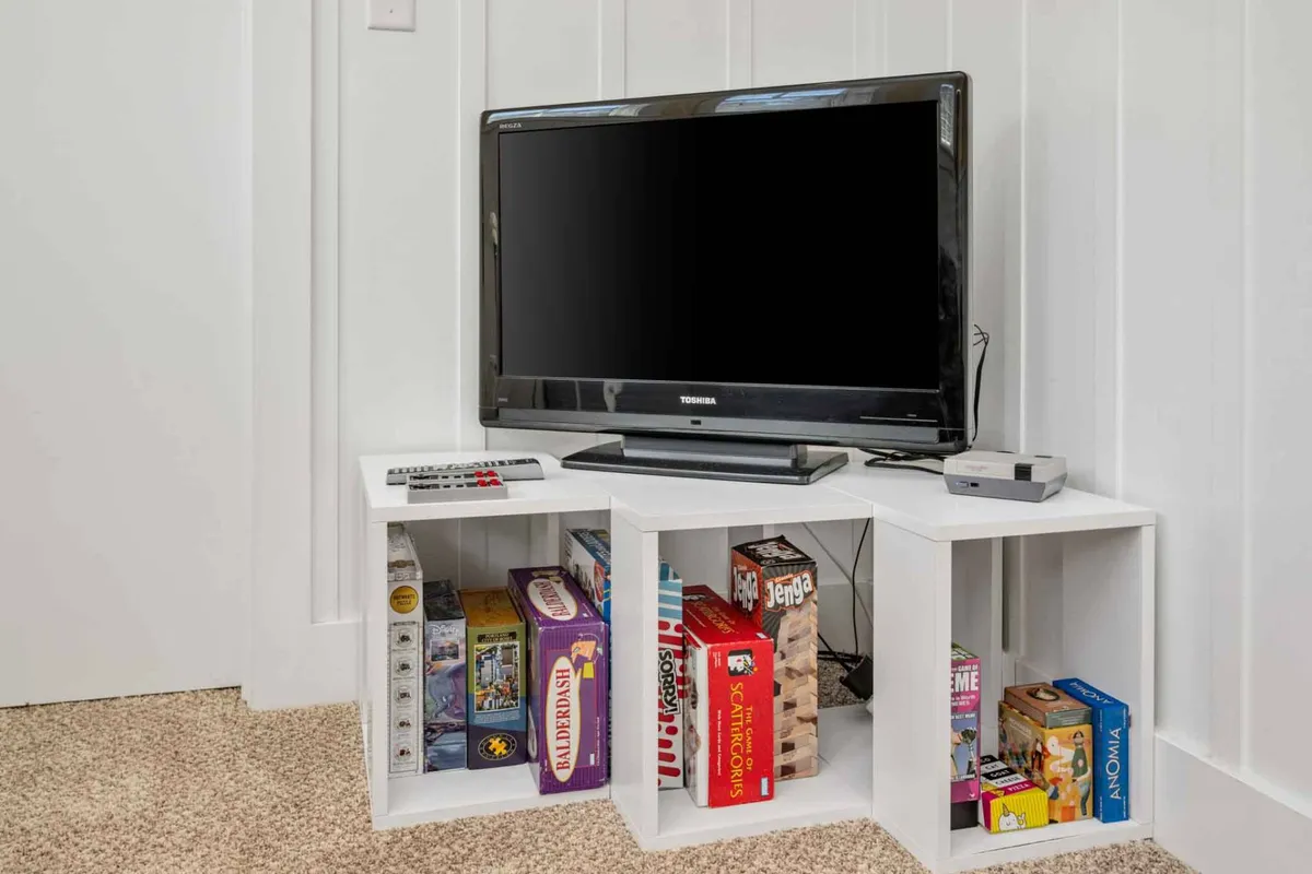 A playful living room with a television, a shelving unit stocked with board games, and comfortable seating. This space is clearly designed for both movie nights and family game sessions, inviting guests to bond and create memories.